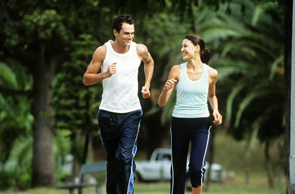 Mid adult man and woman jogging in park,looking in eyes and smiling